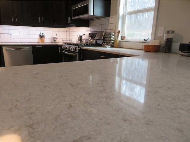24243 Sandusky Rd, Tonganoxie, KS 66086 - kitchen with appliances with stainless steel finishes, dark cabinetry, and tasteful backsplash