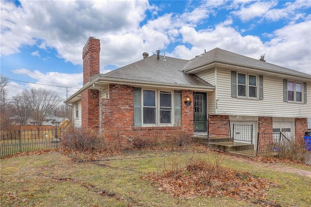 tri-level home with brick siding, a chimney, an attached garage, and fence