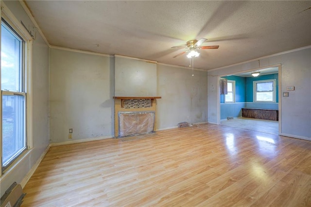 unfurnished living room with a fireplace with flush hearth, a textured ceiling, ornamental molding, and wood finished floors