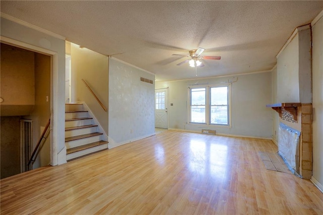 unfurnished living room with ornamental molding, a textured ceiling, and wood finished floors