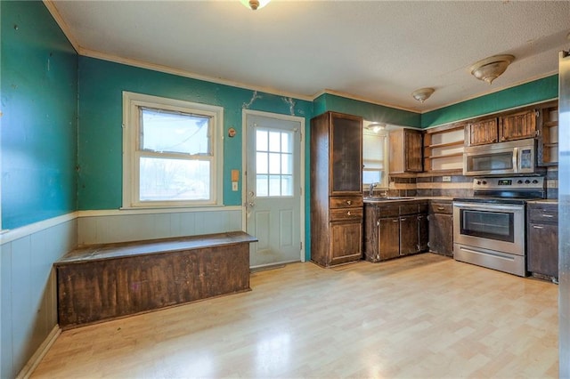 kitchen with a wainscoted wall, open shelves, appliances with stainless steel finishes, and light wood-type flooring