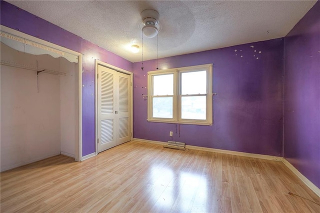 unfurnished bedroom featuring a textured ceiling, wood finished floors, visible vents, a ceiling fan, and baseboards