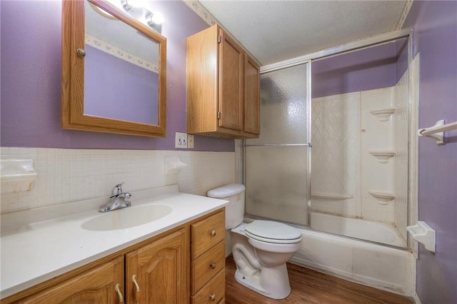 bathroom featuring toilet, enclosed tub / shower combo, wood finished floors, a textured ceiling, and vanity