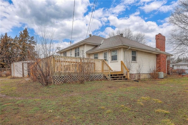 back of property featuring a lawn, a chimney, and a wooden deck