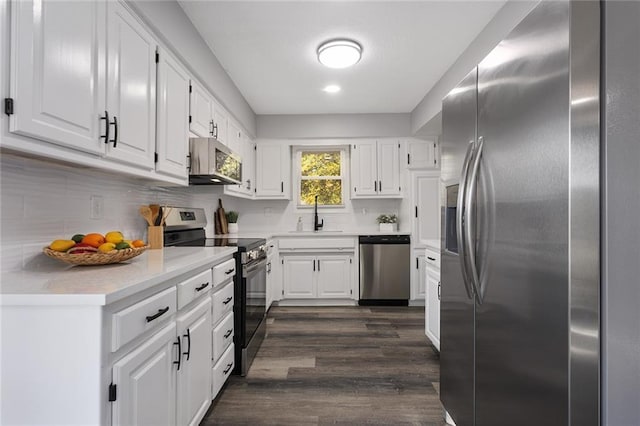 kitchen featuring dark wood-style flooring, stainless steel appliances, tasteful backsplash, white cabinets, and a sink