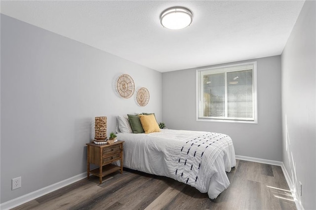 bedroom featuring a textured ceiling, baseboards, and wood finished floors