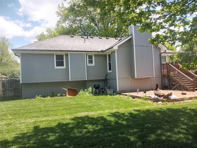 rear view of property with a yard, stairs, roof with shingles, and fence
