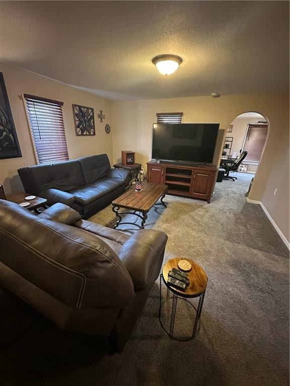 carpeted living room featuring baseboards, arched walkways, and a textured ceiling