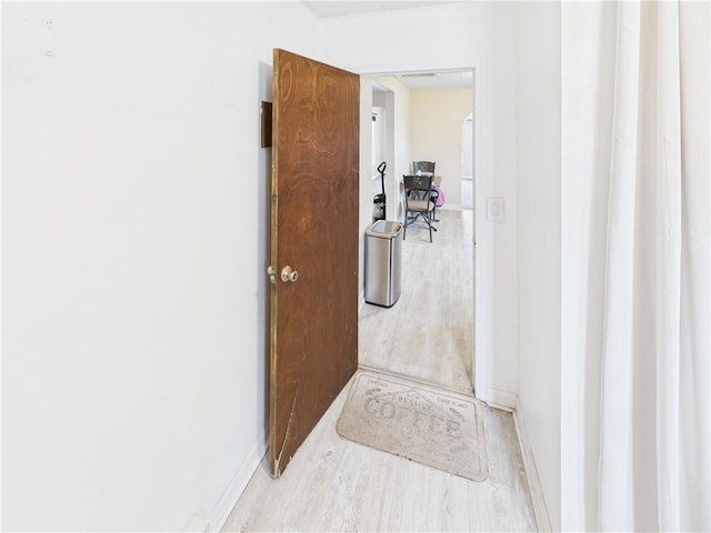 hall with baseboards and wood finished floors