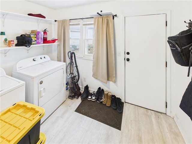 laundry area with laundry area, washing machine and dryer, and light wood-style floors