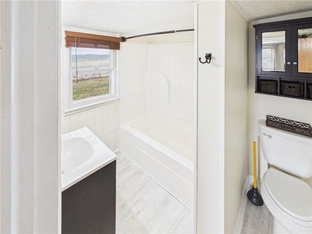 full bath featuring toilet, wood finished floors, a textured ceiling, vanity, and tile walls