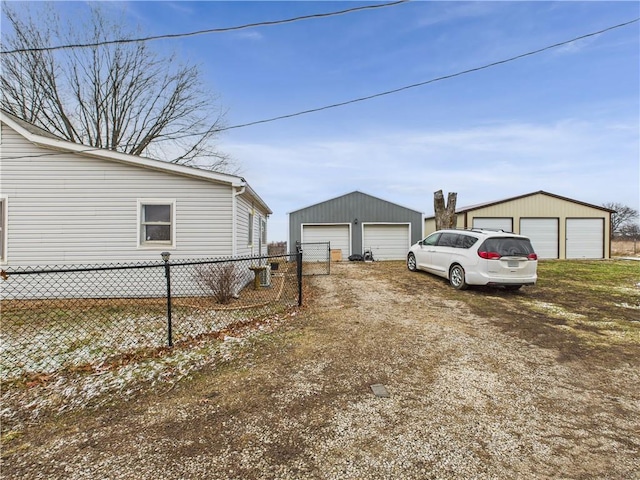 view of yard with a garage, driveway, an outdoor structure, and fence