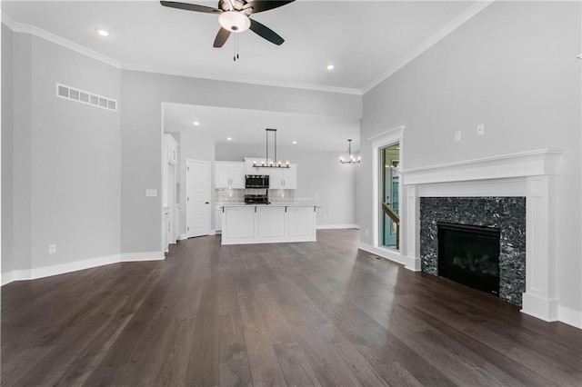 unfurnished living room featuring dark wood-style flooring, crown molding, visible vents, a premium fireplace, and baseboards