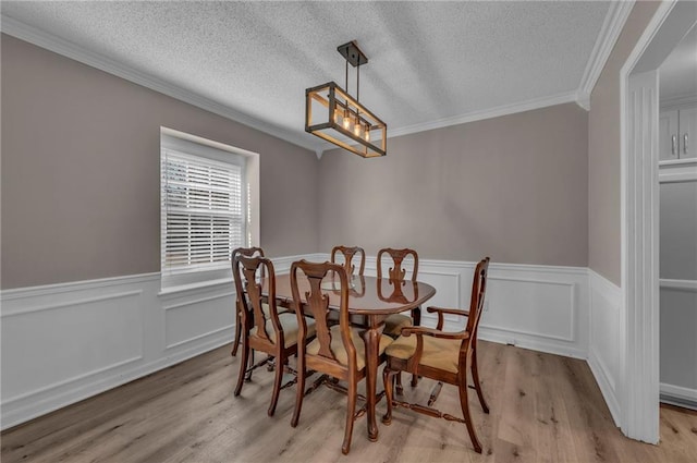 dining space with crown molding, light wood finished floors, and a textured ceiling