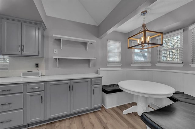 bathroom featuring an inviting chandelier, vaulted ceiling, wood finished floors, and a wainscoted wall