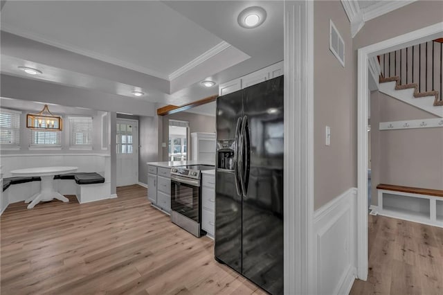 kitchen with visible vents, stainless steel electric stove, ornamental molding, black fridge, and light wood-style flooring