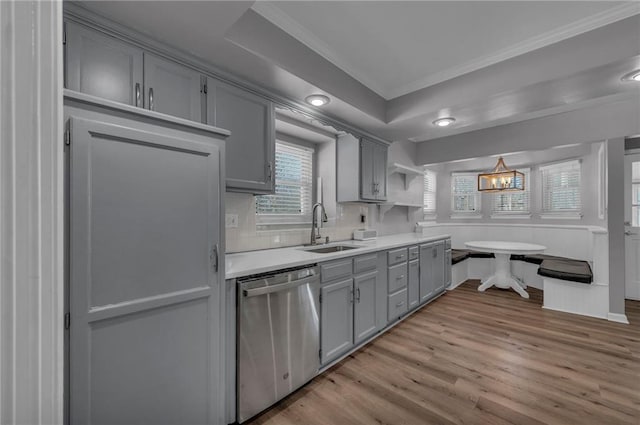 kitchen with light countertops, gray cabinets, stainless steel dishwasher, light wood-style floors, and a sink