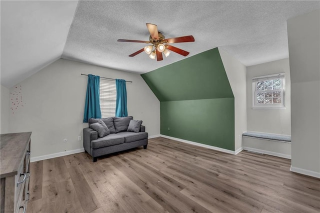 additional living space with baseboards, a textured ceiling, lofted ceiling, and wood finished floors