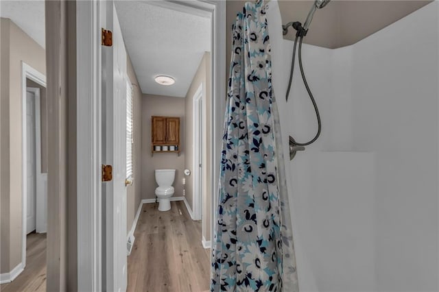 full bathroom featuring toilet, a shower with shower curtain, baseboards, and wood finished floors