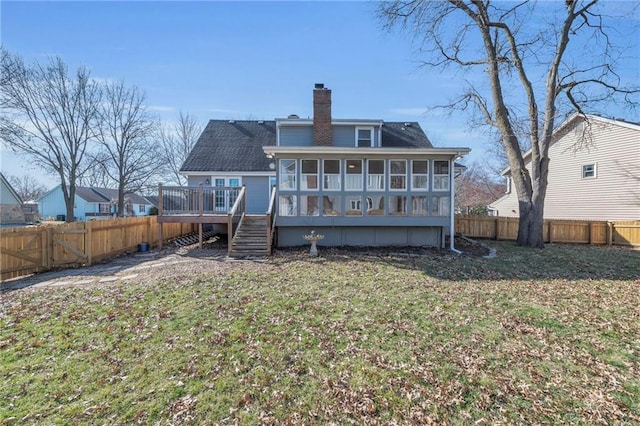 back of house with a wooden deck, a chimney, a fenced backyard, and a sunroom