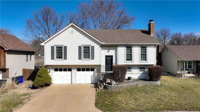 split foyer home with a front lawn, concrete driveway, an attached garage, a shingled roof, and a chimney