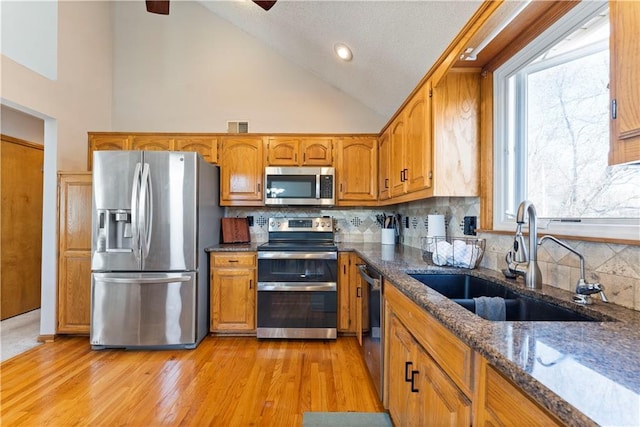 kitchen featuring dark stone countertops, brown cabinetry, visible vents, a sink, and stainless steel appliances