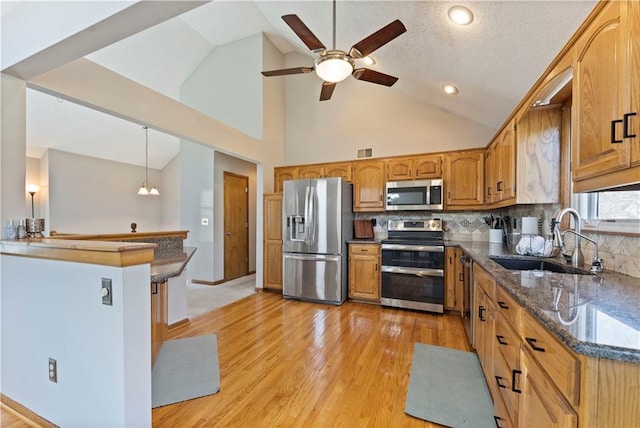 kitchen featuring a ceiling fan, light wood-style flooring, a sink, stainless steel appliances, and brown cabinets