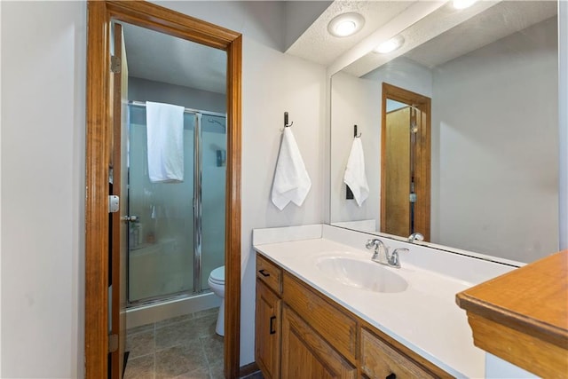 bathroom featuring vanity, a shower stall, toilet, and tile patterned flooring