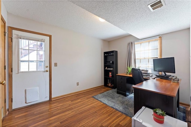 office with plenty of natural light, wood finished floors, visible vents, and a textured ceiling