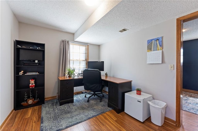 home office featuring visible vents, baseboards, a textured ceiling, and wood finished floors