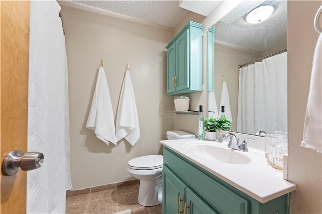 bathroom featuring baseboards, toilet, vanity, tile patterned floors, and a textured ceiling