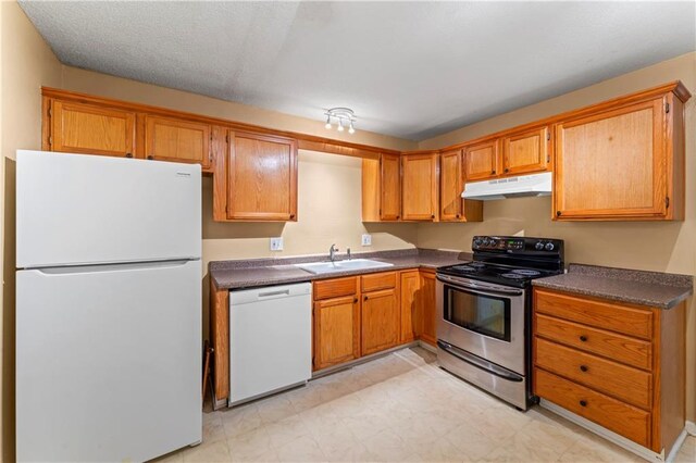 6418 E 150th St, Grandview, MO 64030 - kitchen featuring white appliances, under cabinet range hood, a sink, and dark countertops