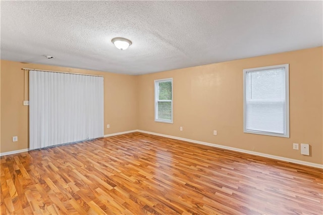 6418 E 150th St, Grandview, MO 64030 - empty room with light wood-style floors, baseboards, and a textured ceiling