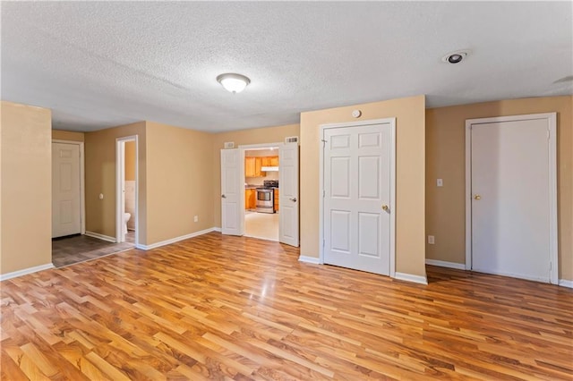 6418 E 150th St, Grandview, MO 64030 - unfurnished bedroom featuring light wood-style floors, baseboards, a textured ceiling, and ensuite bathroom