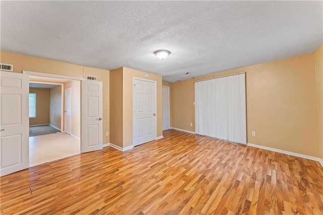 6418 E 150th St, Grandview, MO 64030 - unfurnished bedroom with light wood-style flooring, baseboards, and a textured ceiling
