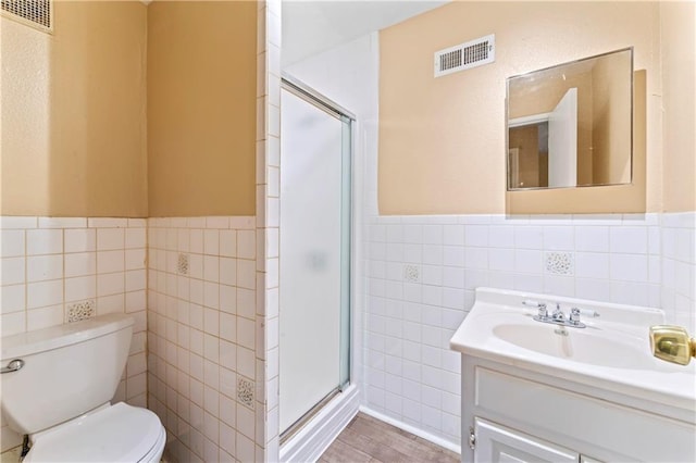 6418 E 150th St, Grandview, MO 64030 - bathroom featuring tile walls, toilet, a stall shower, wainscoting, and vanity