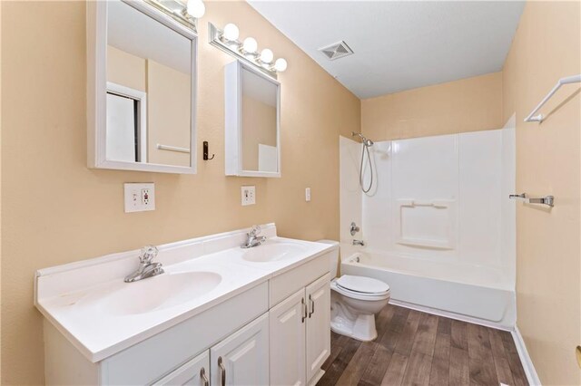6418 E 150th St, Grandview, MO 64030 - full bathroom featuring double vanity, toilet, wood finished floors, and shower / bathtub combination