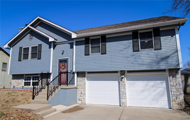 bi-level home featuring concrete driveway, an attached garage, and stone siding