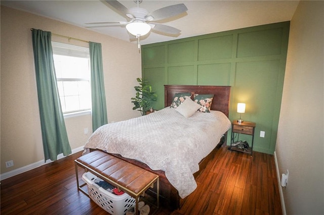 bedroom with a decorative wall, baseboards, ceiling fan, and dark wood-style flooring