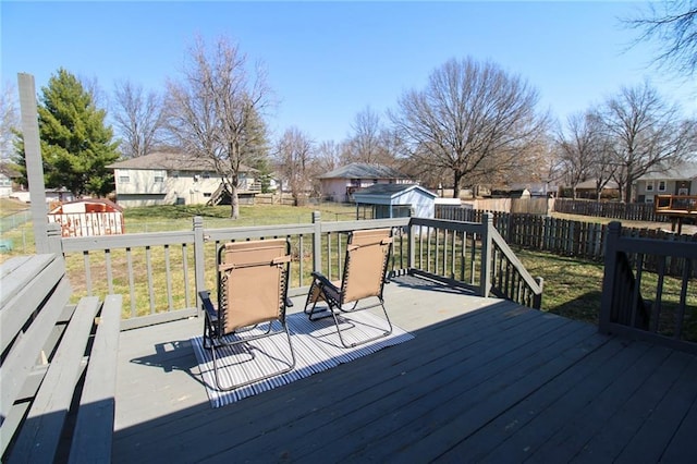 wooden deck with fence, a yard, an outdoor structure, a storage unit, and a residential view