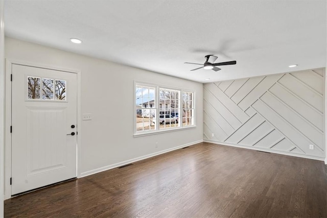 foyer entrance with dark wood-style floors, visible vents, a ceiling fan, and baseboards