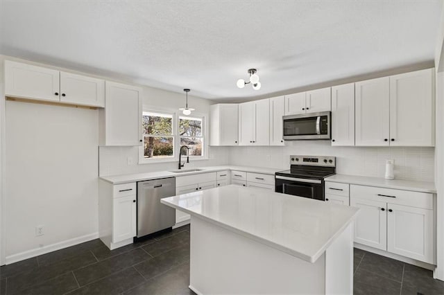 kitchen featuring tasteful backsplash, a sink, stainless steel appliances, white cabinetry, and dark tile patterned flooring