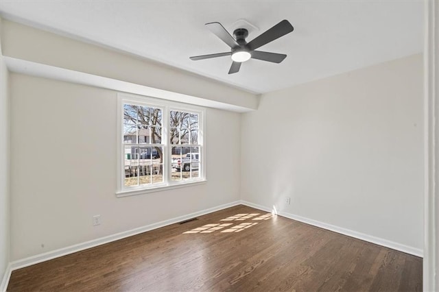 spare room featuring visible vents, a ceiling fan, baseboards, and wood finished floors