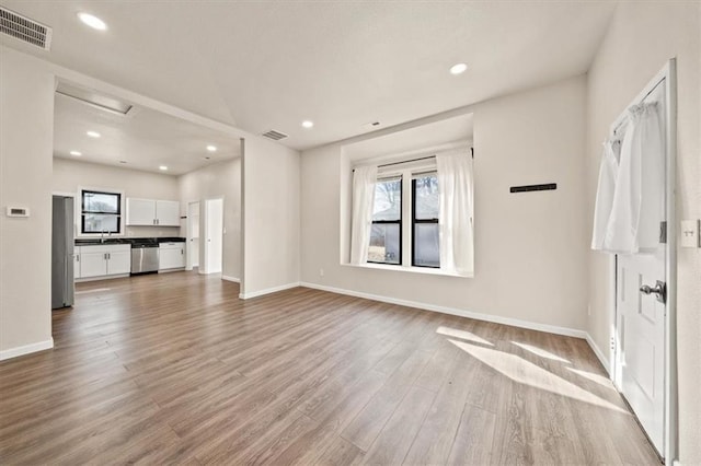 unfurnished living room featuring visible vents, baseboards, and wood finished floors