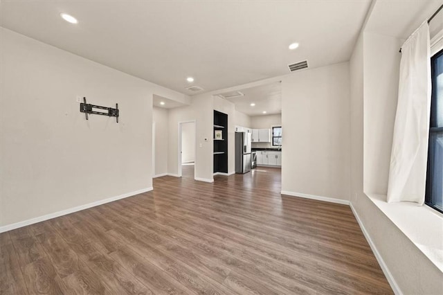 unfurnished living room with dark wood-type flooring, recessed lighting, baseboards, and visible vents