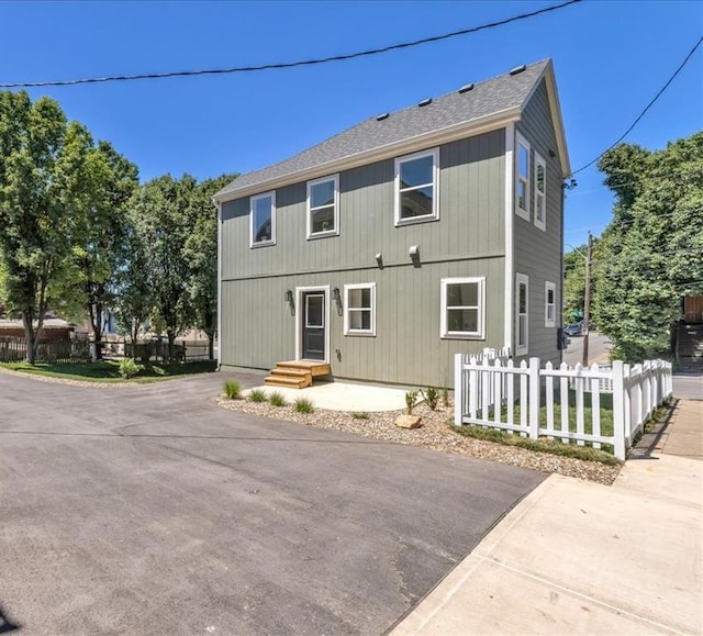 view of front of house featuring a shingled roof and fence