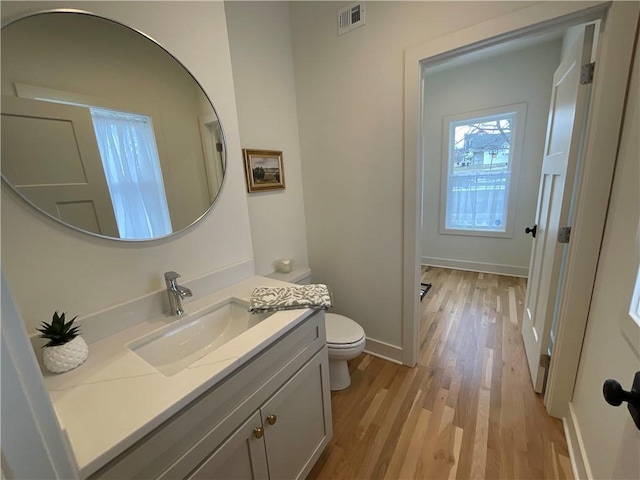 bathroom featuring toilet, wood finished floors, vanity, visible vents, and baseboards