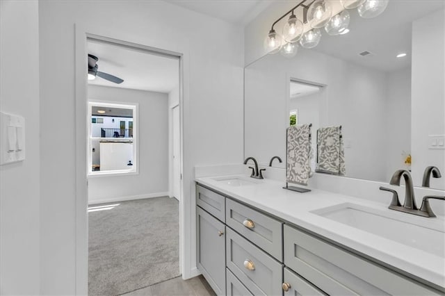 full bath featuring double vanity, a sink, a ceiling fan, and baseboards