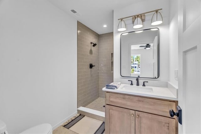 bathroom featuring ceiling fan, toilet, visible vents, vanity, and tiled shower