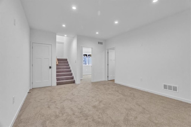 empty room with light carpet, stairway, visible vents, and recessed lighting